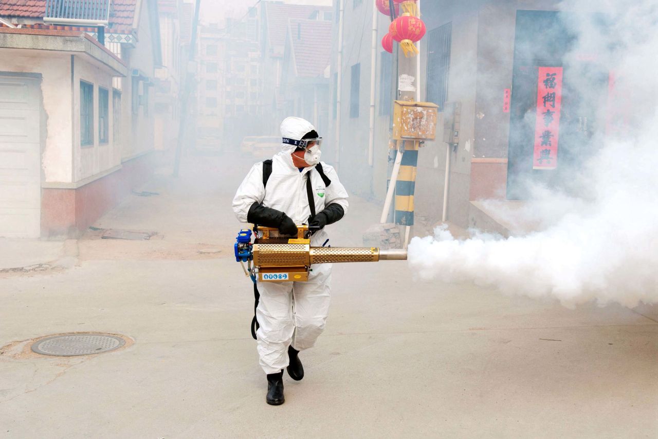 A volunteer wearing protective clothing disinfects a street in Qingdao, China, on January 29.