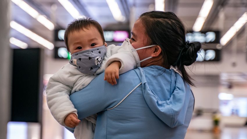 HONG KONG, CHINA - JANUARY 29: A woman carries a baby wearing a protective mask as they exit the arrival hall at Hong Kong High Speed Rail Station on January 29, 2020 in Hong Kong, China. Hong Kong government will deny entry for travellers who has been to Hubei province except for local residents in response to tighten the international travel and border crossing to stop the spread of the virus. (Photo by Anthony Kwan/Getty Images)