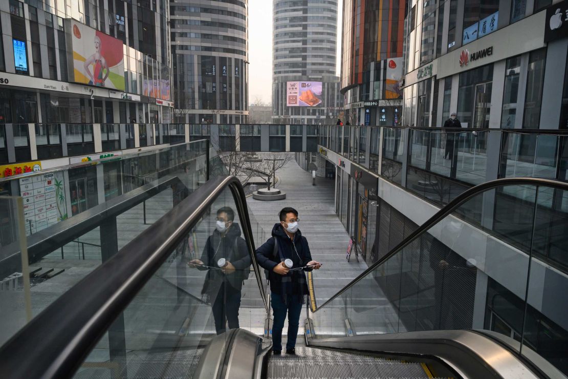 A Chinese man wears a protective mask as he rides an escalator at a large empty shopping area that would usually be busy during the Chinese New Year and Spring Festival holiday on January 28, 2020 in Beijing, China.