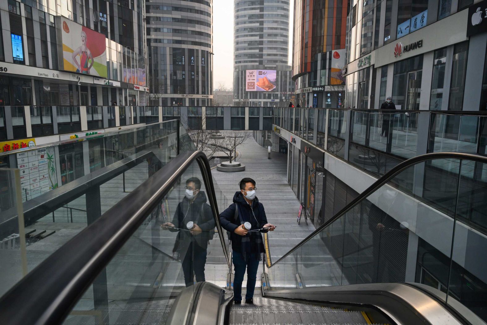 A man wearing a protective mask rides an escalator in a shopping area that would usually be busy during the Chinese New Year in Beijing, on January 28.