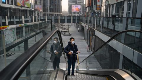 A Chinese man wears a protective mask as he rides an escalator at a large empty shopping area that would usually be busy during the Chinese New Year and Spring Festival holiday on January 28, 2020 in Beijing, China. 