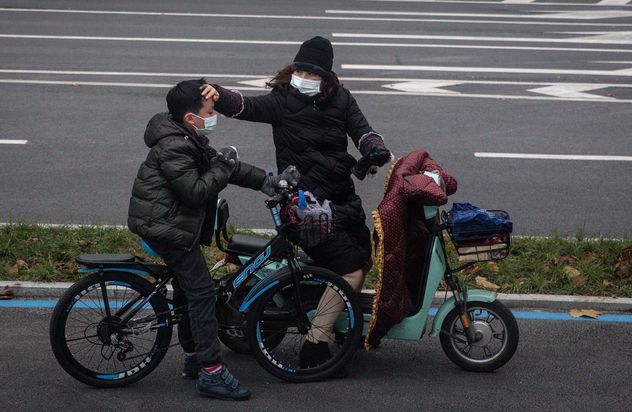 A woman checks her son's forehead on January 27 in Wuhan, China. The coronavirus outbreak began in Wuhan, and the majority of cases in China remain concentrated in Hubei province, where Wuhan is the capital. Wuhan has been under lockdown since January 23, with movement halted in or out of the city, and public transport limited within.