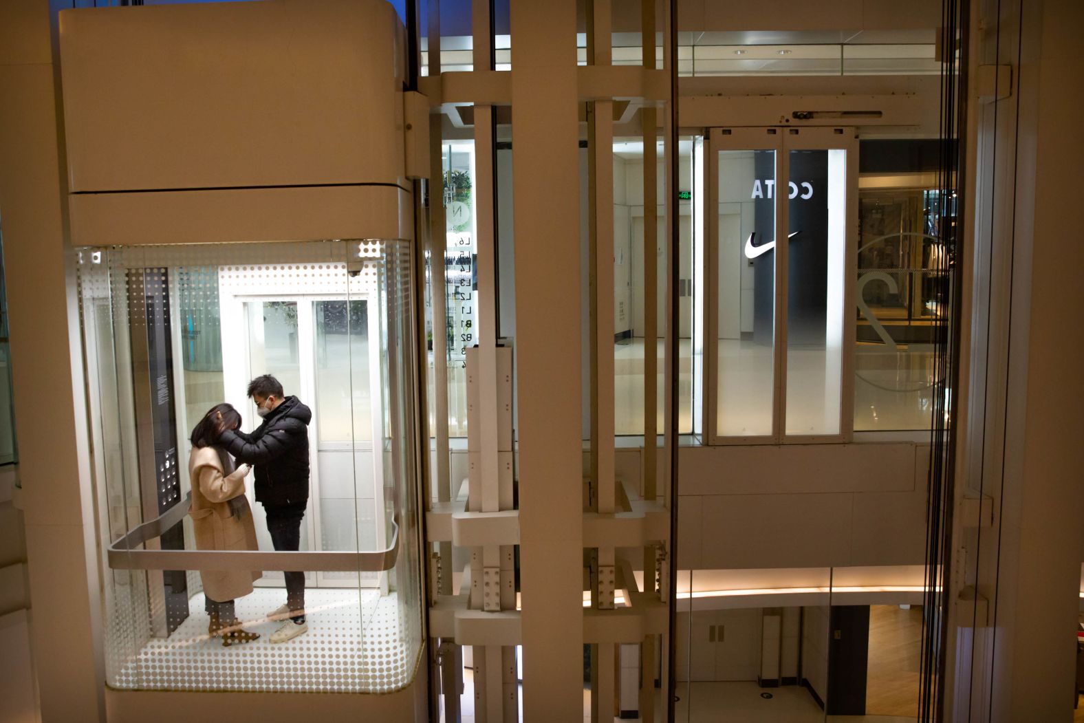 A couple wearing face masks ride an elevator at a nearly empty shopping mall in Beijing on January 29.