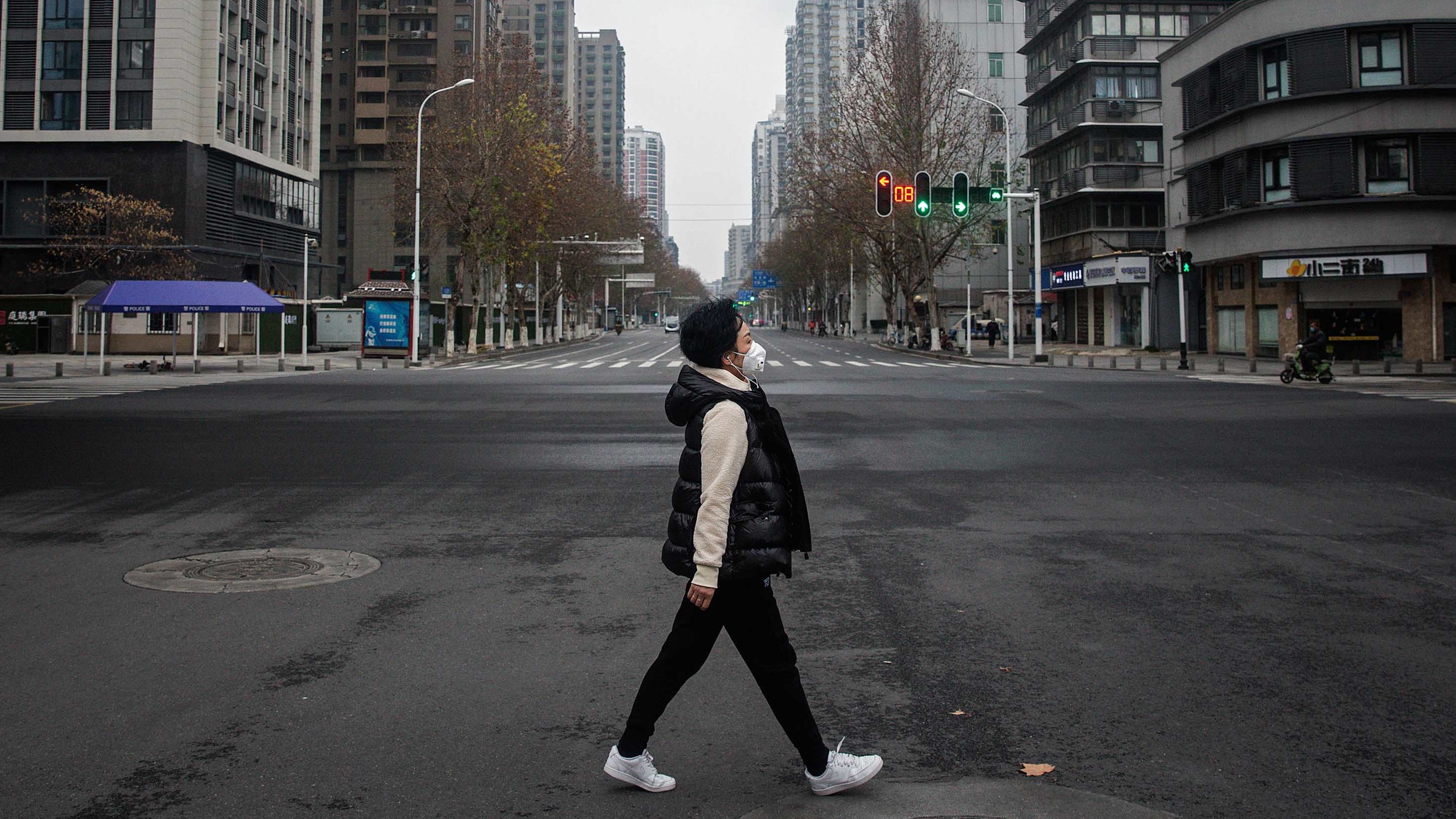 A woman crosses an empty street in Wuhan. The city has been under lockdown since January 23.