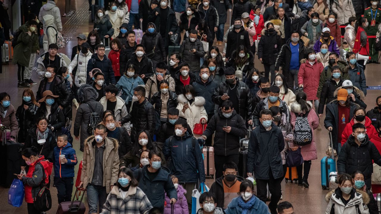 Chinese passengers, most wearing masks, arrive to board trains before the Lunar New Year at a Beijing railway station.