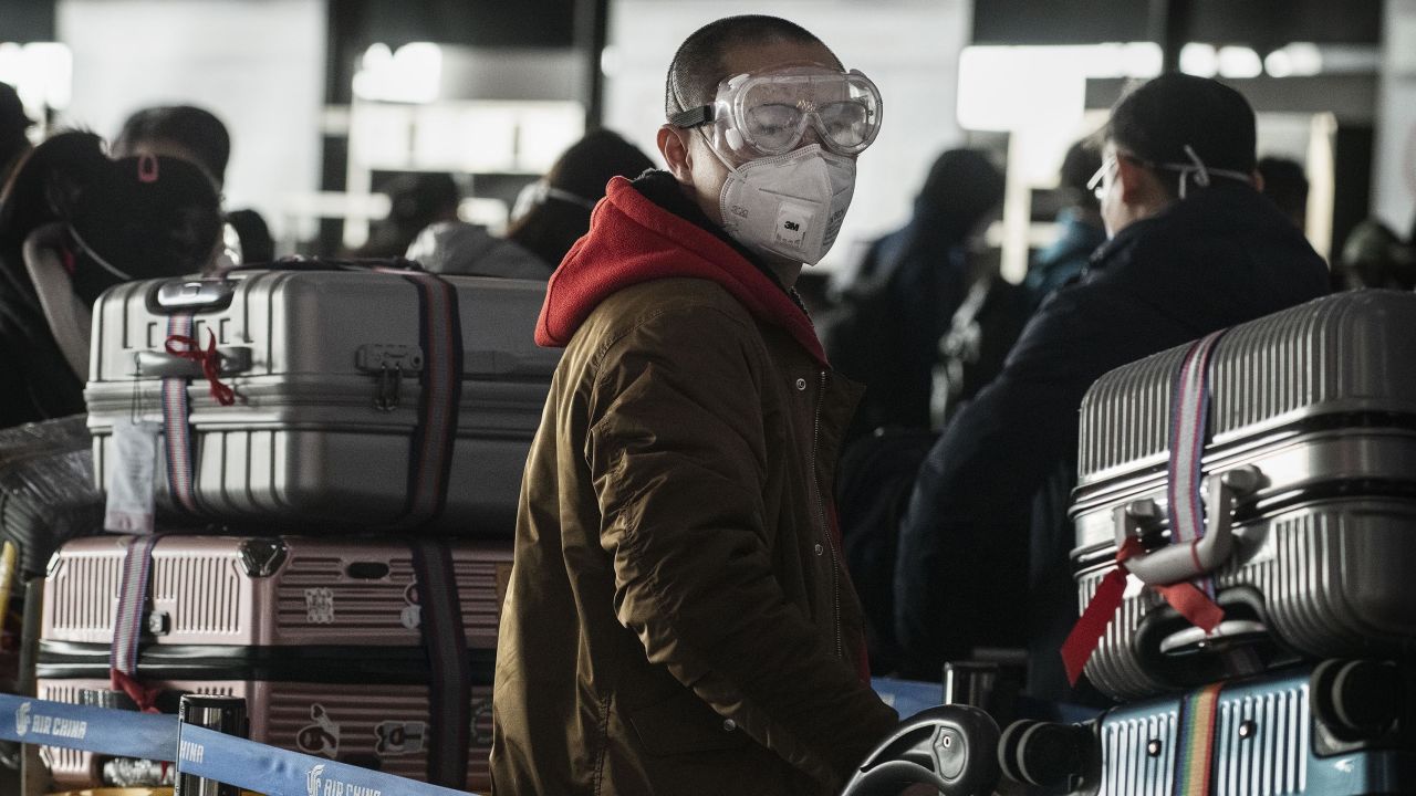A man wears a protective mask and goggles as he lines up to check in to a flight at Beijing Capital Airport on January 30.