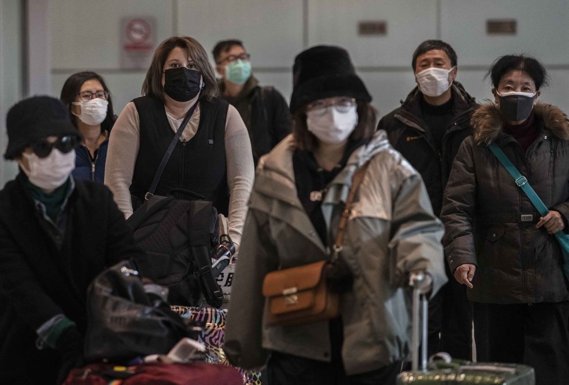 Passengers wear protective masks as they arrive at Beijing Capital Airport.