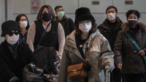 Passengers wear protective masks as they arrive at Beijing Capital Airport.