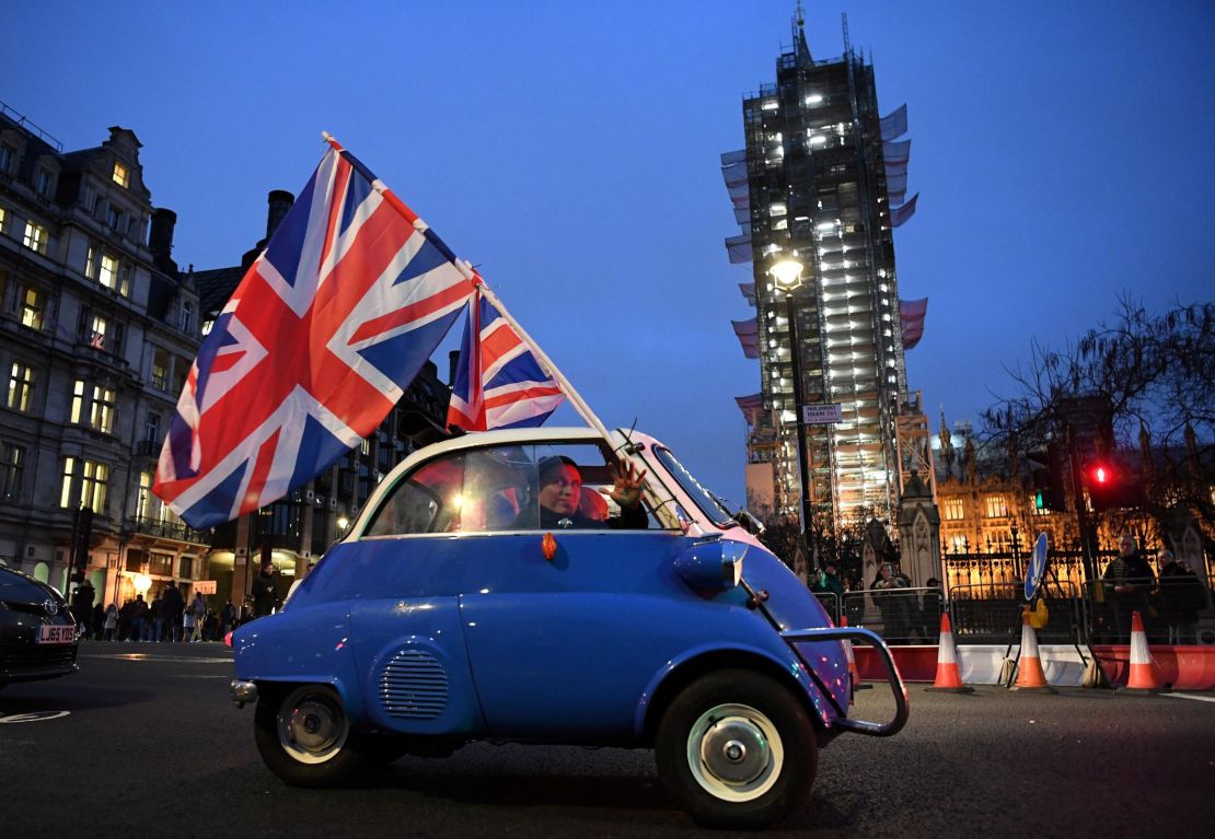 A man waves Union flags from a small car as he drives past Brexit supporters gathering in Parliament Square, near the Houses of Parliament in central London on January 31, 2020 on the day that the UK formally leaves the European Union.