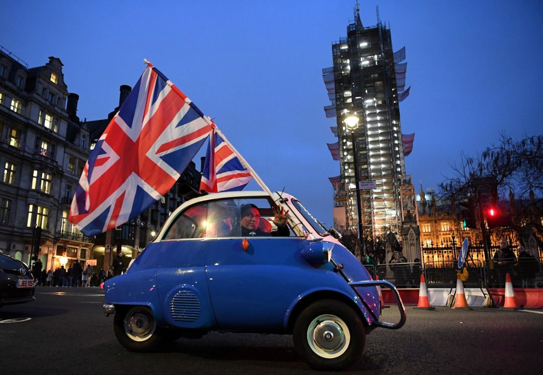 A man waves Union flags from a small car as he drives past Brexit supporters gathering in Parliament Square, near the Houses of Parliament in central London on January 31, 2020 on the day that the UK formally leaves the European Union.