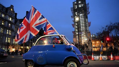 A man waves Union flags from a small car as he drives past Brexit supporters gathering in Parliament Square, near the Houses of Parliament in central London on January 31, 2020 on the day that the UK formally leaves the European Union.