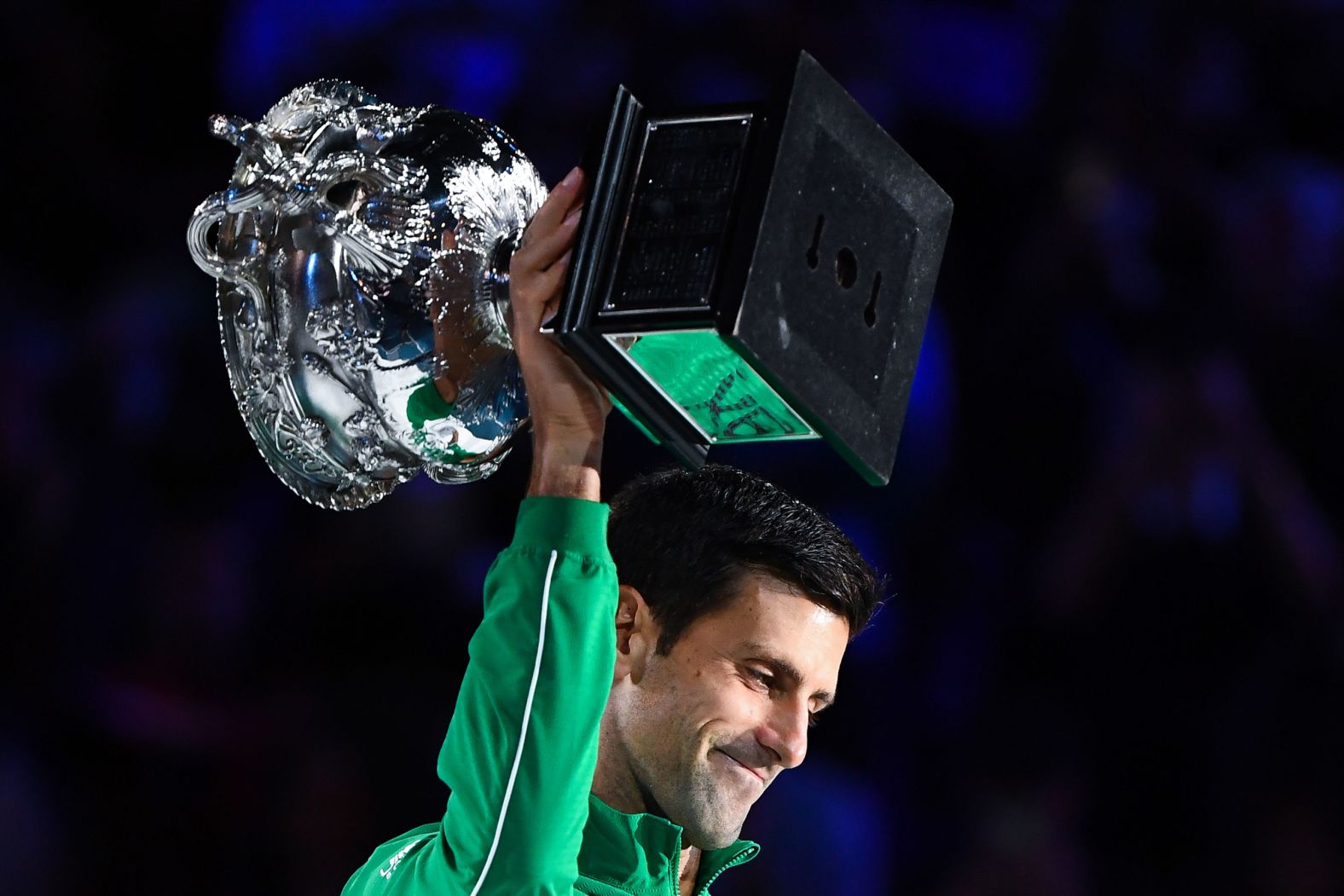 Djokovic holds up the Norman Brooks Challenge Cup trophy.