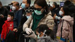 A woman wears a protective face mask and gloves while waiting to go through immigration at Beijing airport on February 1, 2020.