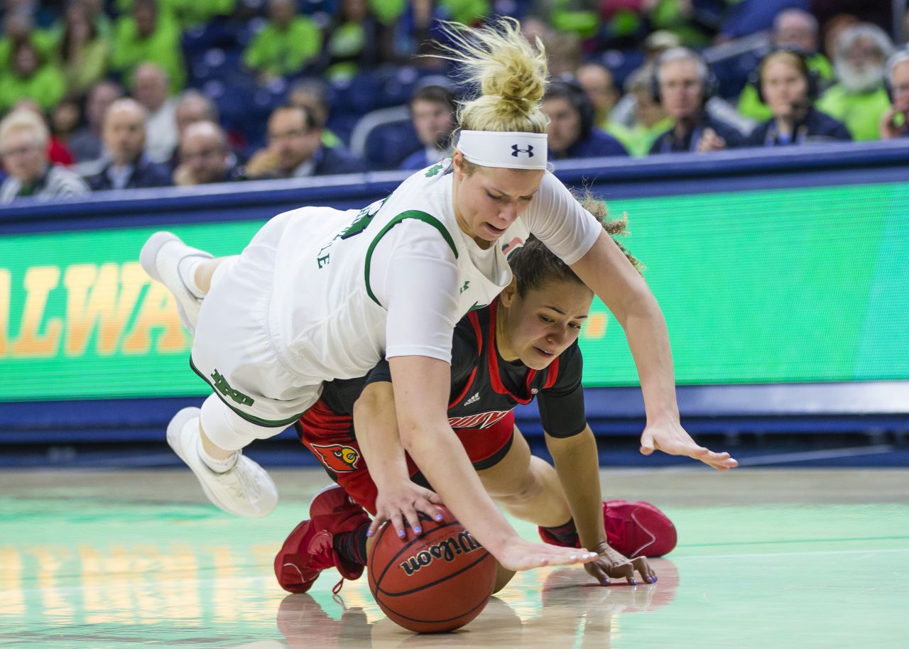 Notre Dame's Sam Brunelle jumps over Louisville's Mykasa Robinson as they chase down a loose ball on Thursday, January 30.