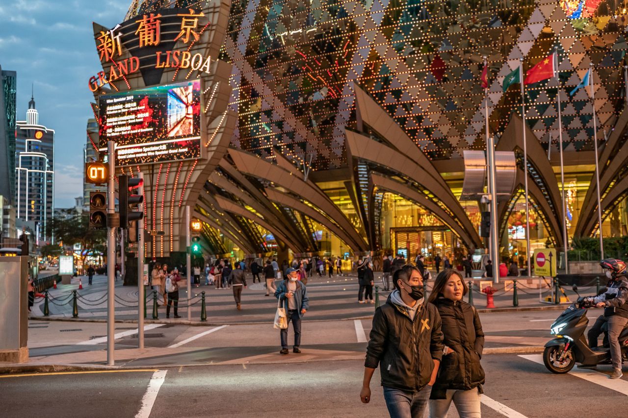 People wearing face masks walk in front of the Grand Lisboa Hotel on January 28, 2020 in Macao.