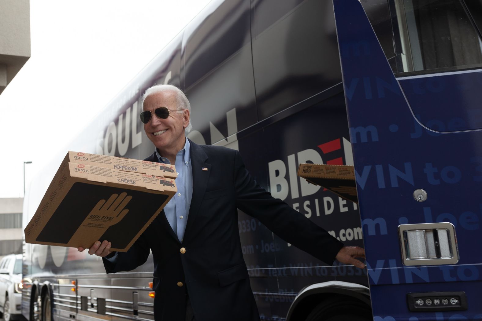 Biden carries pizza boxes before speaking at an event in Des Moines on February 3.