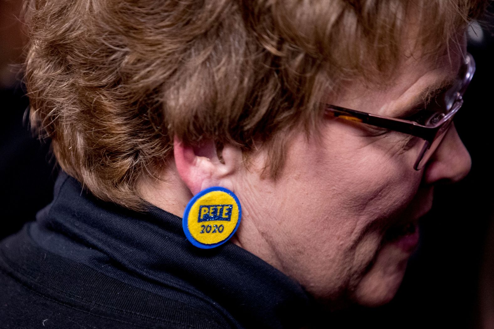 A Buttigieg supporter wears campaign earrings as she says hello to him at an office in West Des Moines.