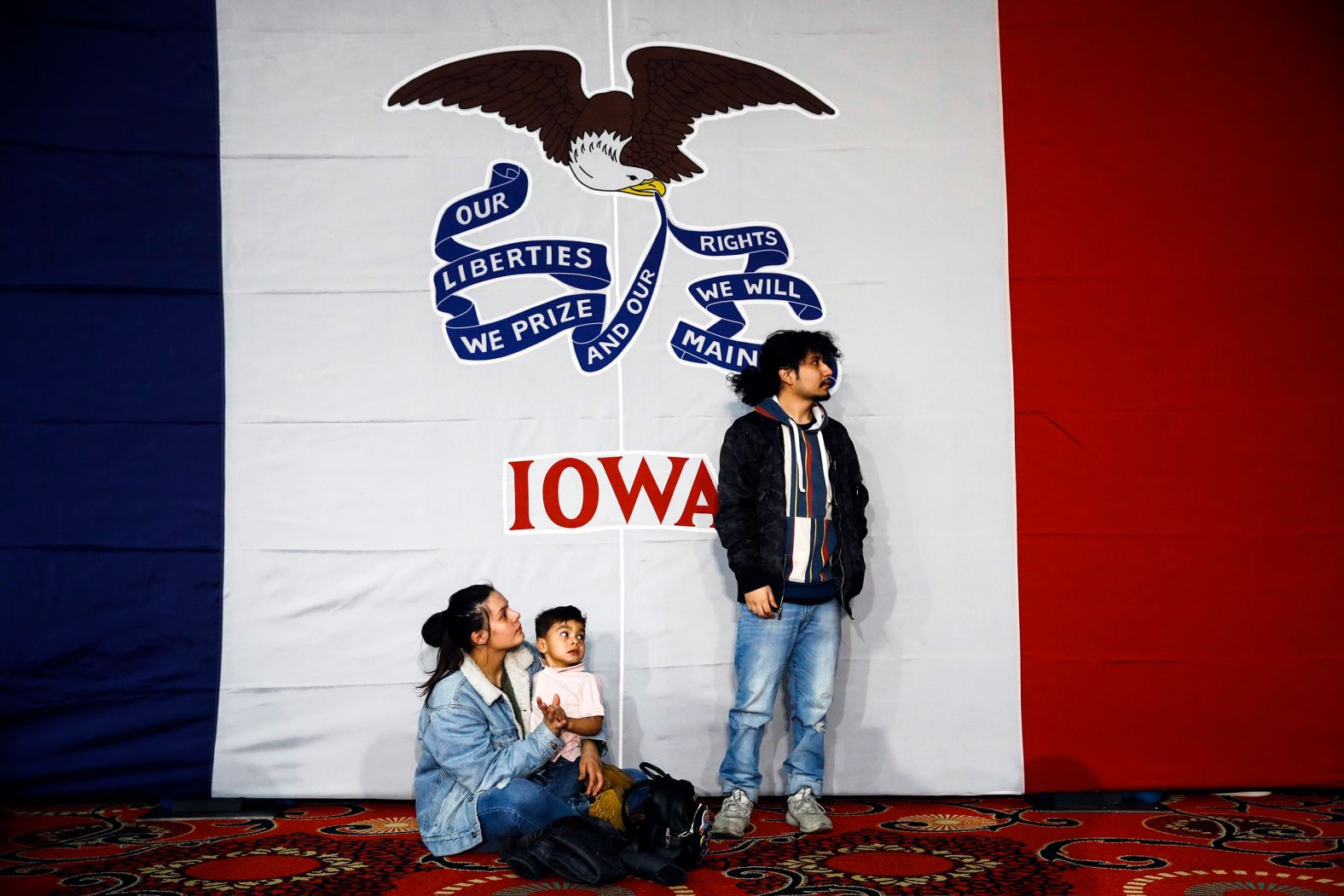 Natalie Serrano and Isaac Garcia — along with their 2-year-old son, Leonel — wait for caucus returns to come in at a Sanders rally in Des Moines.