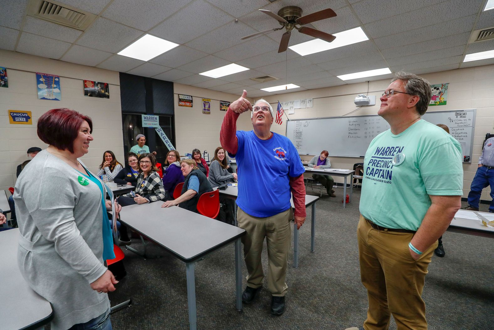 Caucus chairman Steve King flips a coin to determine which candidate has to drop a delegate in Algona, Iowa. At left is Sarah Casey, a Klobuchar supporter. On the right is Chris Brown, a Warren supporter.