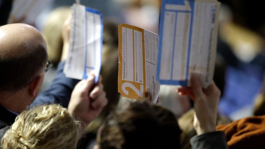 Caucus goers seated in the section for Democratic presidential candidate former Vice President Joe Biden hold up their first votes as they are counted at the Knapp Center on the Drake University campus in Des Moines, Iowa, Monday, Feb. 3, 2020. (AP Photo/Gene J. Puskar)