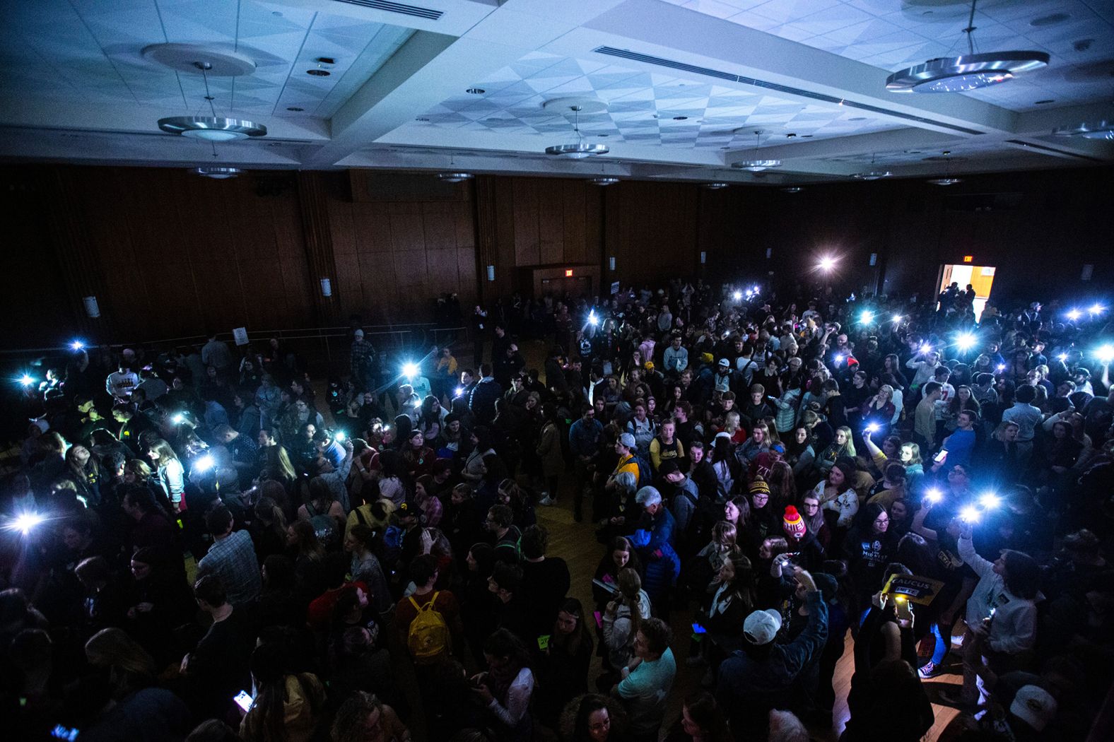 University of Iowa students shine their phone lights after the overhead lights went out during a caucus in Iowa City.