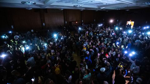 University of Iowa students shine their phone lights after the overhead lights went out during a caucus in Iowa City.