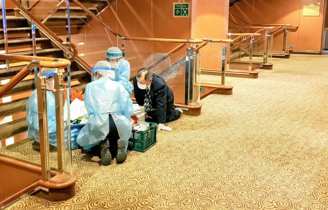 Health workers are seen on board the Diamond Princess in this photograph taken by a passenger.