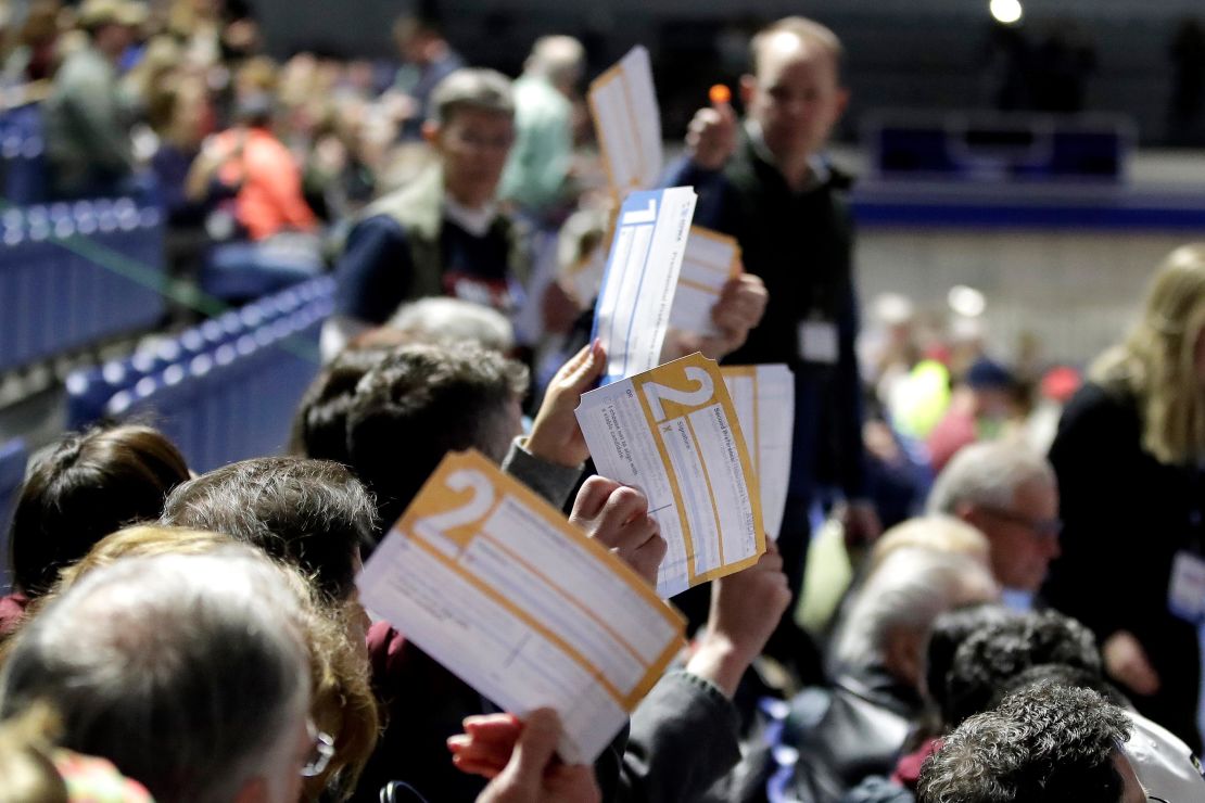 Caucus goers seated in the section for Democratic presidential candidate former Vice President Joe Biden hold up their first votes as they are counted at the Knapp Center on the Drake University campus in Des Moines, Iowa.