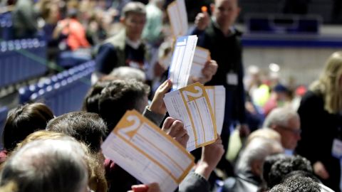 Caucus goers seated in the section for Democratic presidential candidate former Vice President Joe Biden hold up their first votes as they are counted at the Knapp Center on the Drake University campus in Des Moines, Iowa.