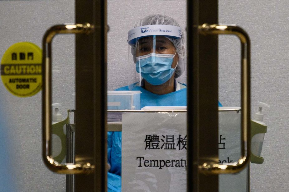 A medical worker wearing protective gear waits to take the temperature of people entering Princess Margaret Hospital in Hong Kong.