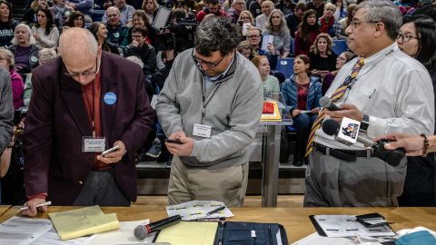 A precinct secretary and volunteer conduct an initial head count at a caucus site in Des Moines.
