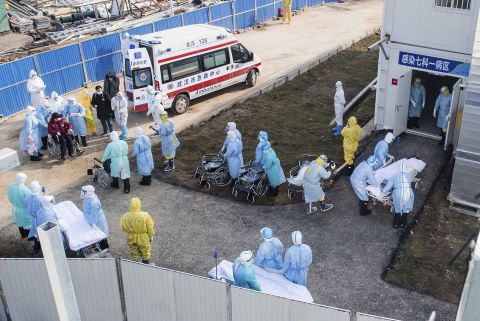 Medical workers in protective suits help transfer patients to a newly completed field hospital in Wuhan.