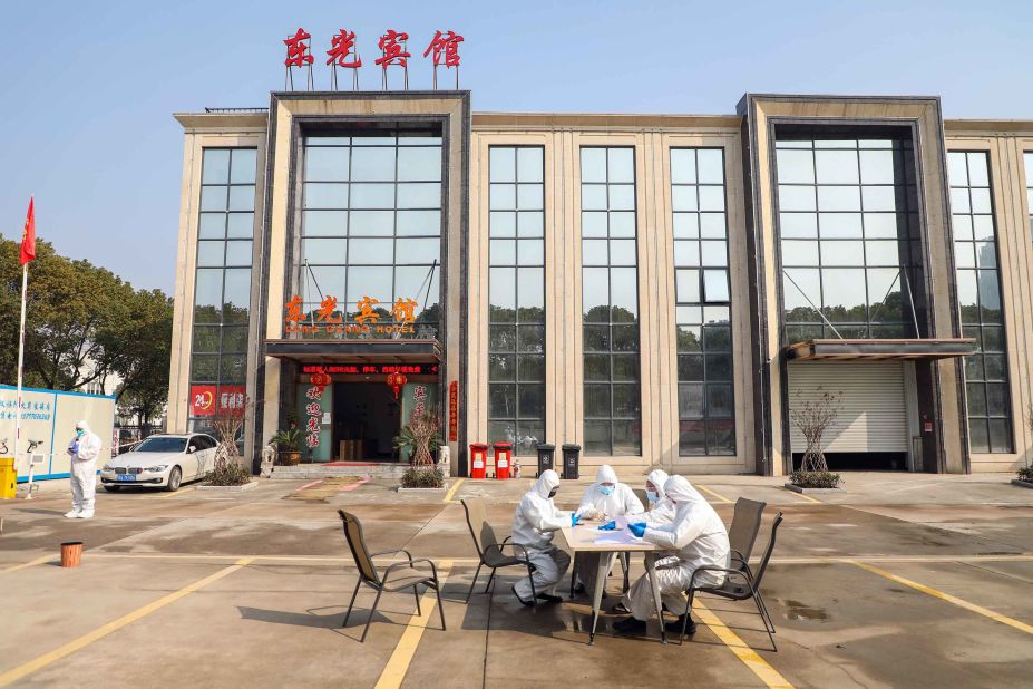 People wearing protective overalls talk outside a Wuhan hotel housing people in isolation on February 3.