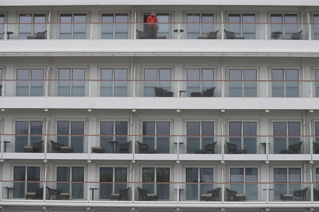 A passenger wearing a facemask looks out from the cabin of the World Dream cruise ship in Kai Tak cruise terminal Hong Kong on Wednesday.