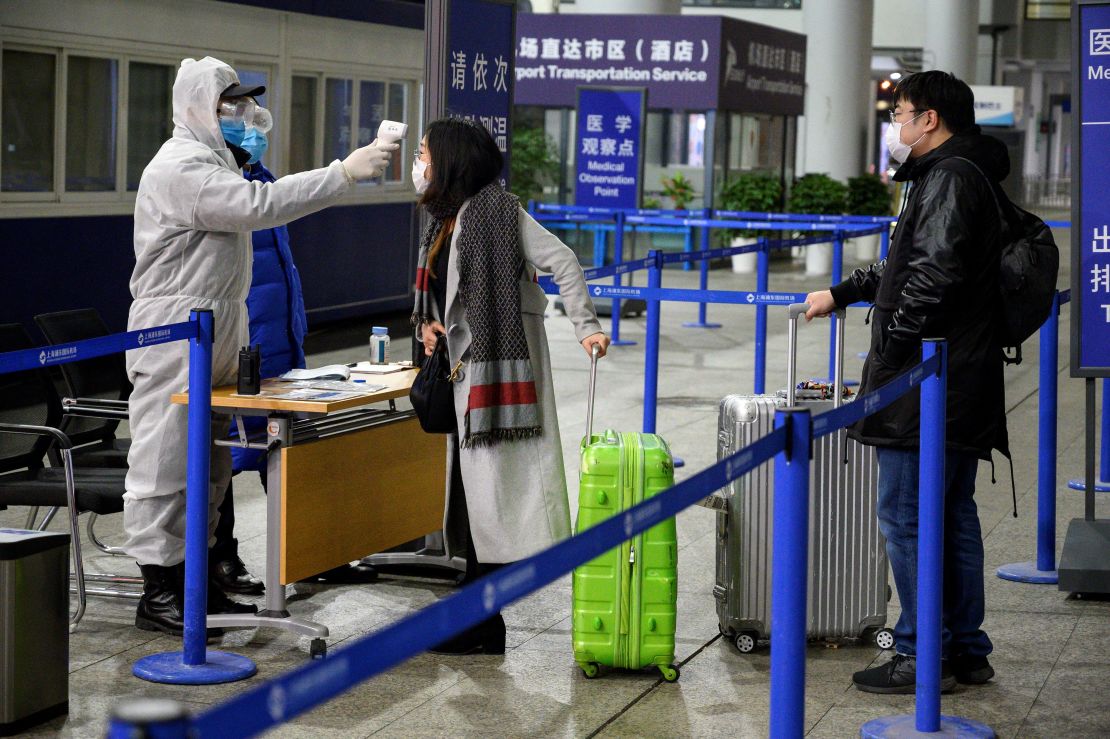 A security personnel checks the temperature of passengers arriving at the Shanghai Pudong International Airport in Shanghai on February 4, 2020. 