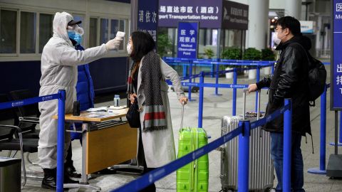 A security personnel checks the temperature of passengers arriving at the Shanghai Pudong International Airport.