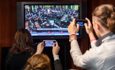 Reporters in Washington take photos of a television as they watch the Senate vote to acquit President Donald Trump on February 5.