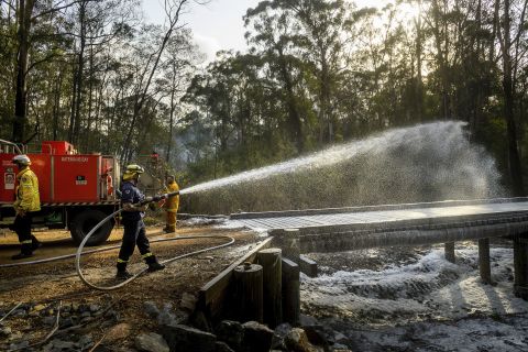 A firefighter coats a bridge with foam as a bushfire burns near Moruya, Australia, on Saturday, January 25.