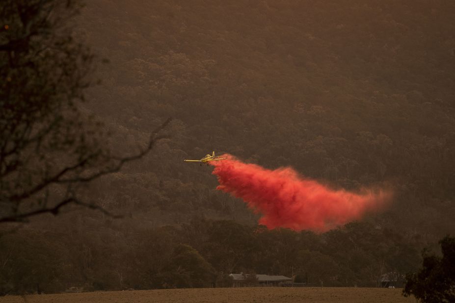 An airplane dumps fire retardant behind houses at the foot of Mount Tennent as  fire creeps through the Namadgi National Park in Canberra on Thursday, January 30.