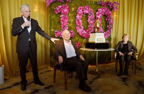 Douglas looks on as his son Michael makes a speech at his 100th birthday party in 2016.
