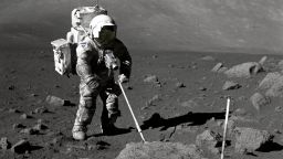 Geologist-Astronaut Harrison Schmitt, Apollo 17 lunar module pilot, uses an adjustable sampling scoop to retrieve lunar samples during the second extravehicular activity (EVA-2), at Station 5 at the Taurus- Littrow landing site. The cohesive nature of the lunar soil is born out by the "dirty" appearance of Schmitt's space suit. A gnomon is atop the large rock in the foreground. The gnomon is a stadia rod mounted on a tripod, and serves as an indicator of the gravitational vector and provides accurate vertical reference and calibrated length for determining size and position of objects in near-field photographs. The color scale of blue, orange and green is used to accurately determine color for photography. The rod of it is 18 inches long. The scoop Dr. Schmitt is using is 11 3/4 inches long and is attached to a tool extension which adds a potential 30 inches of length to the scoop. The pan portion, blocked in this view, has a flat bottom, flanged on both sides with a partial cover on the top. It is used to retrieve sand, dust and lunar samples too small for the tongs. The pan and the adjusting mechanism are made of stainless steel and the handle is made of aluminum.
