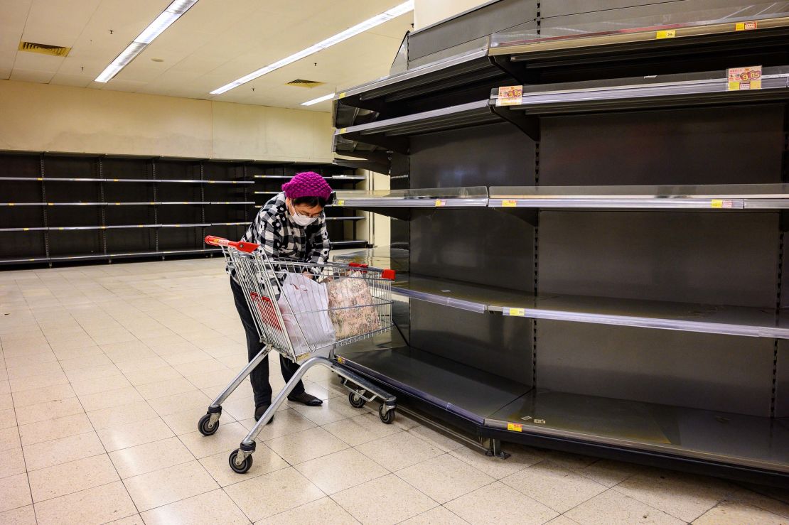 A shopper next to bare supermarket shelves, usually stocked with toilet paper and kitchen rolls, in Hong Kong on February 6, 2020.