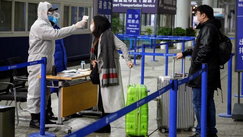 Security personnel check the temperature of passengers arriving at the Shanghai Pudong International Airport on February 4.