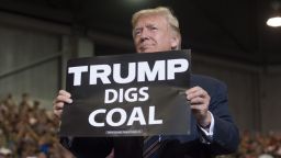 US President Donald Trump holds up a "Trump Digs Coal" sign as he arrives to speak during a Make America Great Again Rally at Big Sandy Superstore Arena in Huntington, West Virginia, August 3, 2017. / AFP PHOTO / SAUL LOEB        (Photo credit should read SAUL LOEB/AFP via Getty Images)
