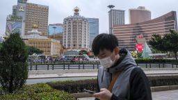 A pedestrian wearing a protective face mask walks past the Casino Lisboa, operated by SJM Holdings Ltd., left, and Wynn Casino resort, operated by Wynn Resorts Ltd., in Macau, China, on Wednesday, Feb. 5, 2020.