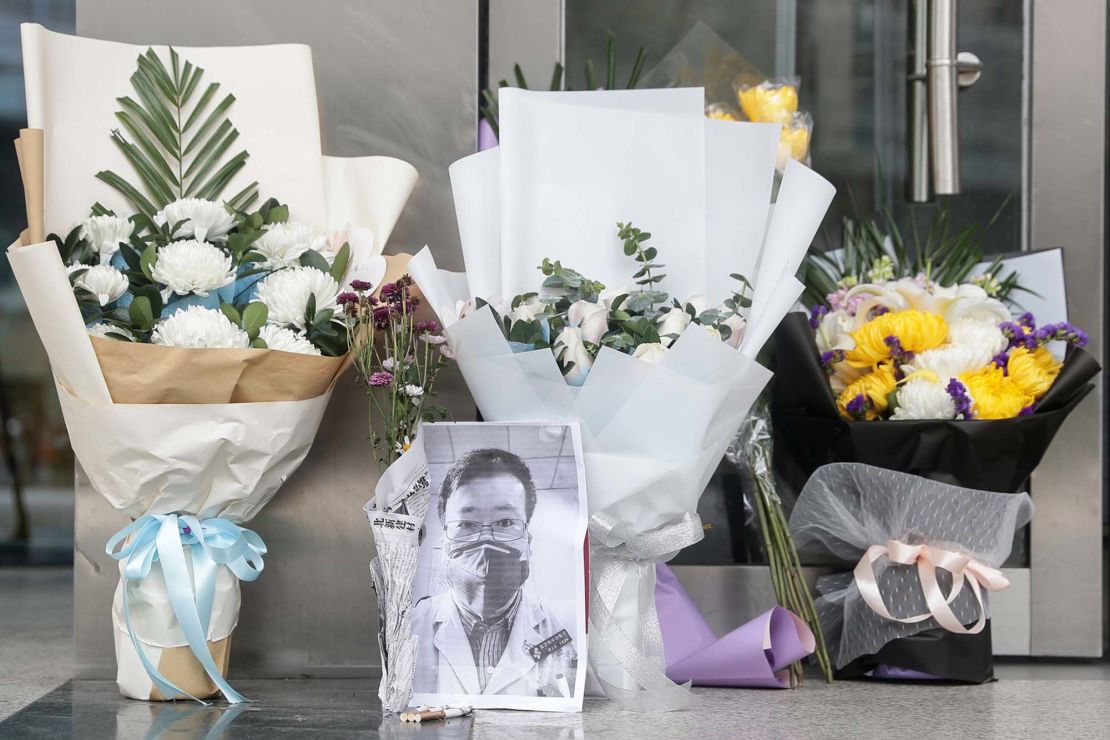 A photo of the late ophthalmologist Li Wenliang is seen with flower bouquets at the Houhu Branch of Wuhan Central Hospital in Wuhan on Friday.