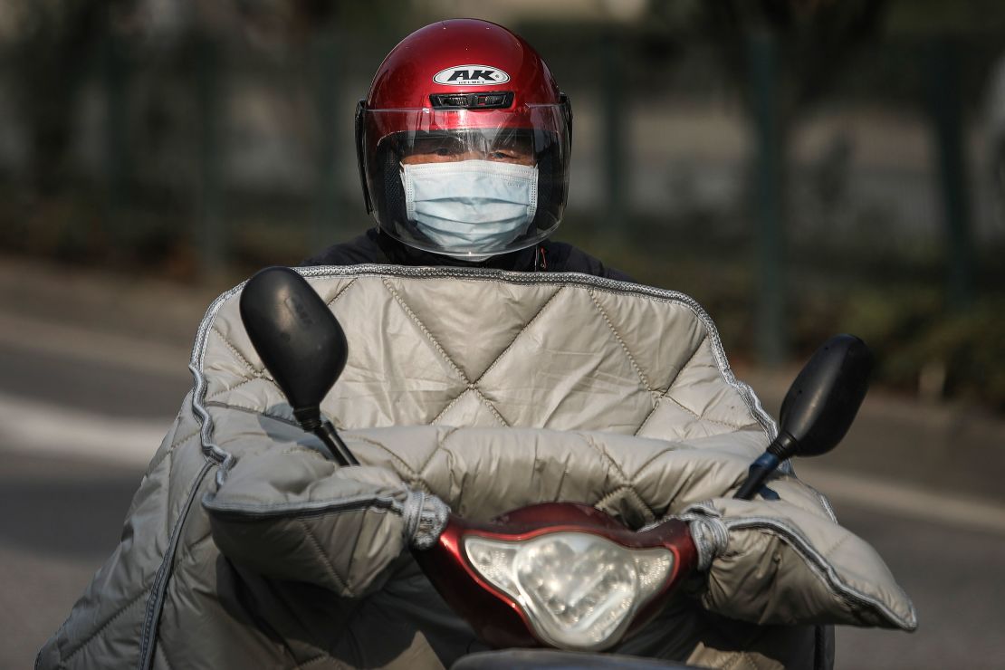 A resident wears a protective mask while riding a scooter on February 5, 2020 in Wuhan, Hubei province, China.