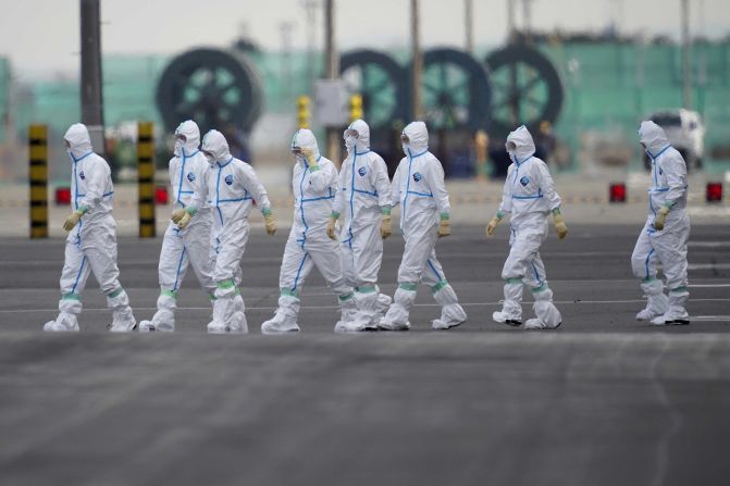 Workers in protective gear walk near the Diamond Princess cruise ship docked in Yokohama, Japan.