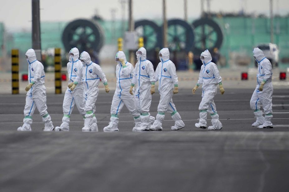 Workers in protective gear walk near the Diamond Princess cruise ship docked in Yokohama on February 7.