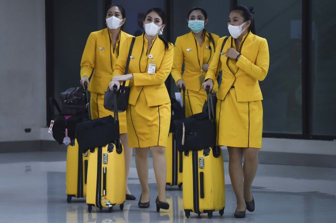Flight attendants wearing face masks make their way through the Don Mueang Airport in Bangkok on February 7, 2020.